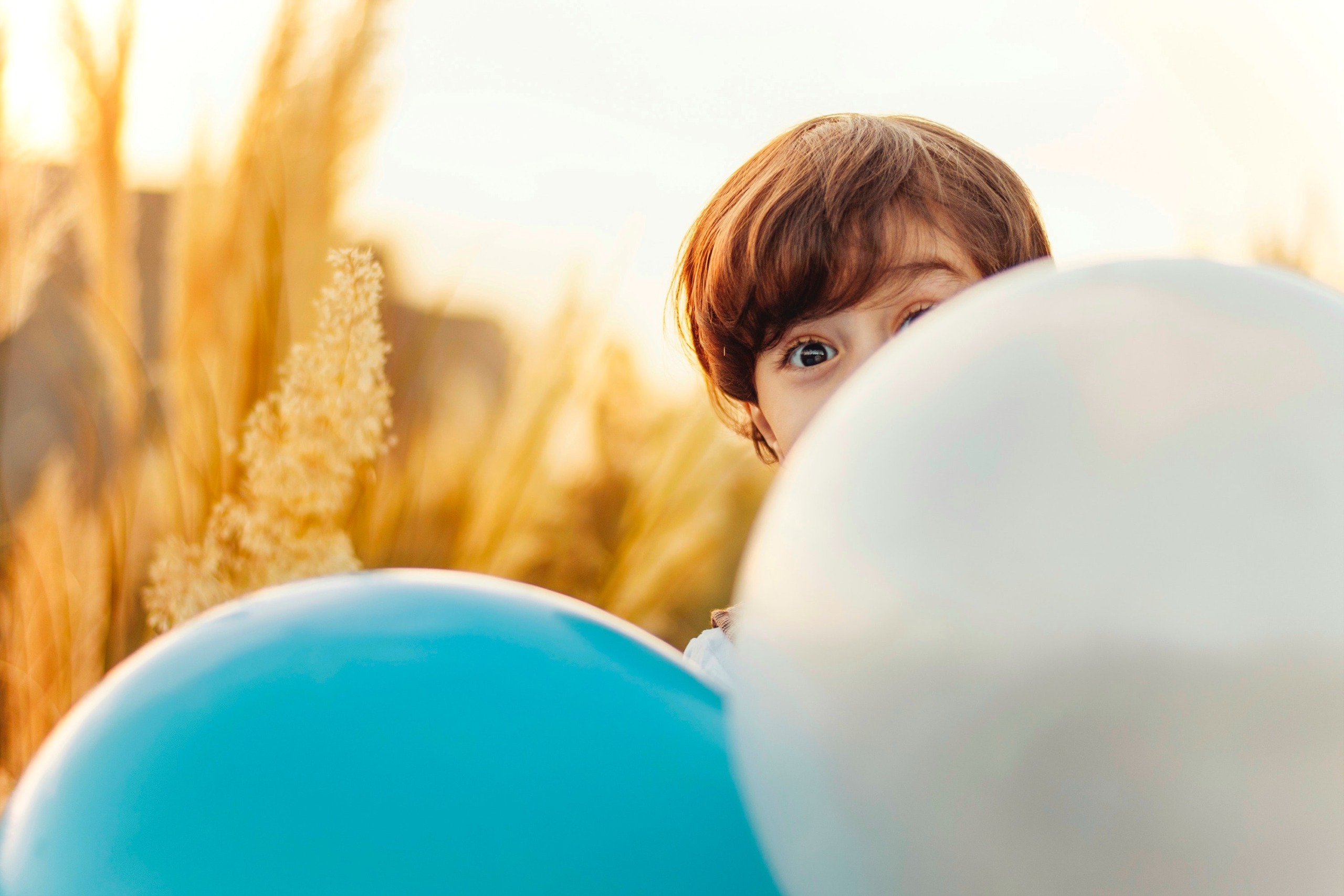 Ein Kind schaut durch Luftballons